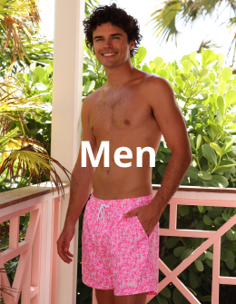 Man on a balcony wearing a pink floral swimsuit by Kulani Kinis brand.