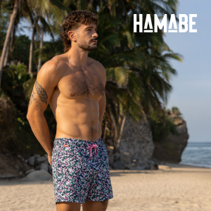 Man on a beach wearing floral swim shorts from the brand Hamabe.