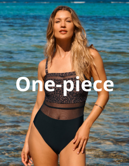 A woman standing by the water, wearing a leopard-print one-piece swimsuit from the Turquoise Couture brand.