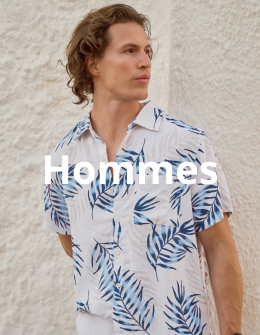 &nbsp;Homme contre un mur portant une chemise au motig palmier et un pantalon blanc de la marque Off The Beach.