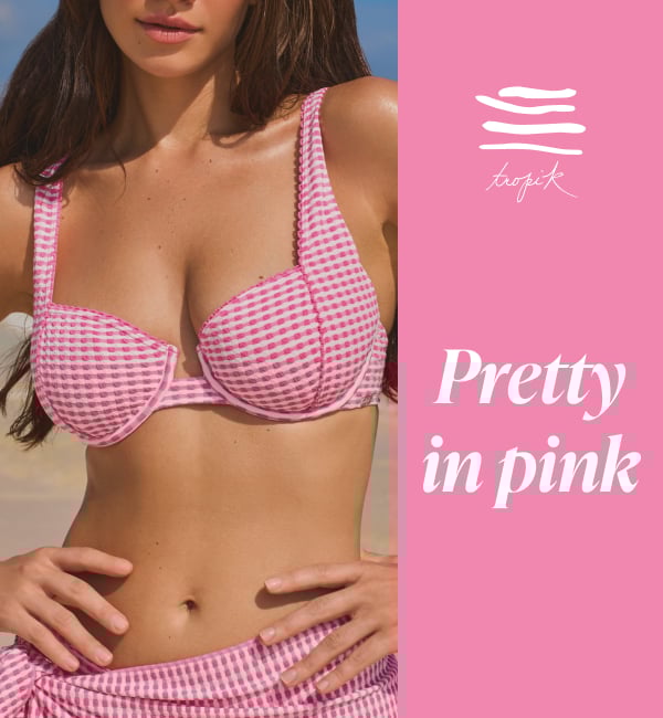 A woman on the beach wearing pink and white plaid bikini set from Tropik brand. 