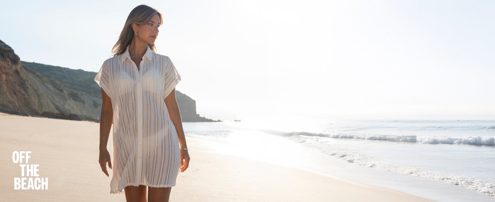 Femme marchant sur la plage, v&ecirc;tue d&rsquo;une chemise en crochet blanche. 