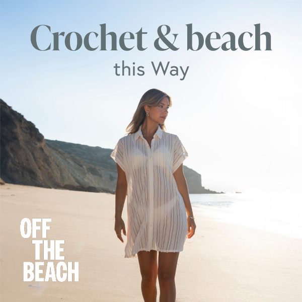 Woman walking on the beach wearing a white crochet chemise.