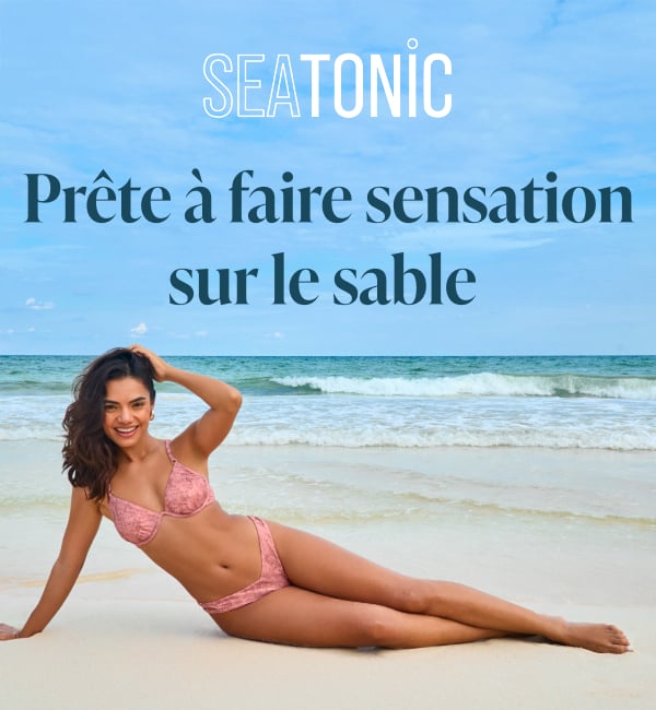 Femme allong&eacute;e sur la plage, portant un bikini rose &agrave; imprim&eacute; serpent de la marque Seatonic. 