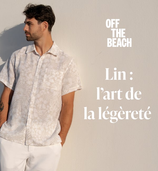 Un homme acc&ocirc;t&eacute; sur un mur portant une chemise en lin au motif floral et un pantalon en lin blanc. 