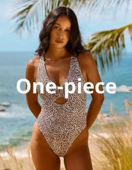 A woman under a tree, posing with her hands behind her back, wearing a leopard-print one-piece swimsuit from the brand Santemare.