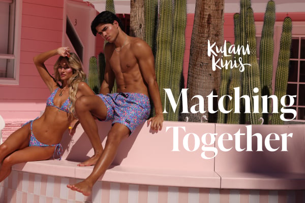 A woman wearing a bikini set and a man wearing matching swim trunks from the brand Kulani Kinis.