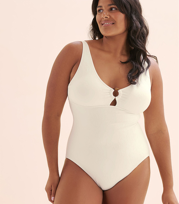 Woman wearing a white one‑piece swimsuit by the brand Turquoise Couture. 