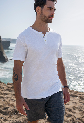 Man on the beach wearing a white Off The Beach T-shirt.	