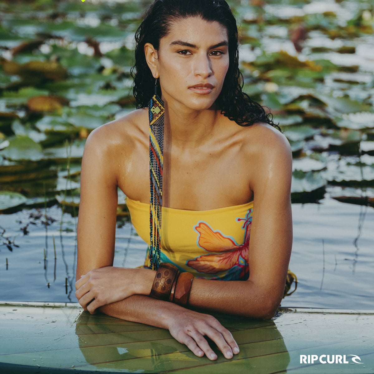Woman in the water wearing a colourful one-piece swimsuit from the Rip Curl x FARM Rio collaboration.