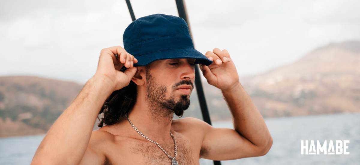 Man on a boat holding a bucket hat by Hamabe on his head