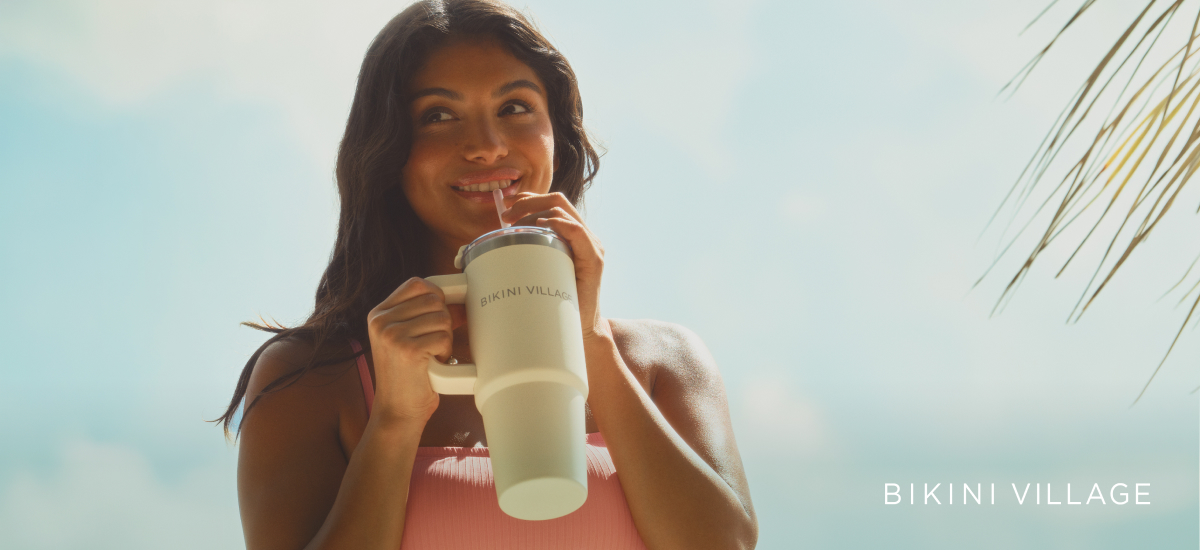 Woman drinking out of a White Bikini Village tumbler
