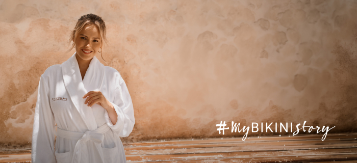 Woman wearing a white robe from Bikini Village.