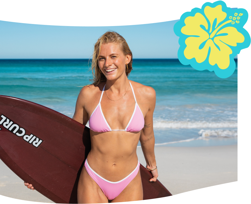 Woman on the beach holding a surf board wearing a pink and white triangle bikini set by Rip Curl.