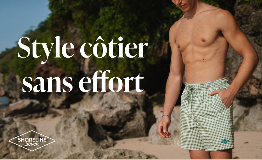 Homme sur la plage avec une main dans la poche d’un maillot au motif à carreaux vert et blanc de la marque Shoreline Seven.